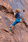 Ein 6-jähriger Junge seilt sich ab, während er im Hunter Canyon bei Moab, Utah, das Klettern lernt.