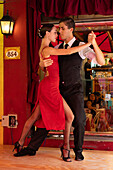 An attractive young couple dances the tango on El Caminito in the La Boca barrio of Buenos Aires, Argentina.