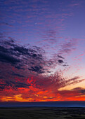 A portrait of a sunset sky with the waxing two-day-old crescent Moon amid colourful clouds over the prairie. This was from Writing-on-Stone Provincial Park in southern Alberta, on June 8, 2024. Taken from "Sunset Point" at the west end of the park.