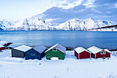 Bunte Holzrorbu mit Schnee bedeckt in der eisigen Landschaft am Fjord, Djupvik, Olderdalen, Lyngenfjord, Lyngen Alpen, Troms og Finnmark, Norwegen, Skandinavien, Europa