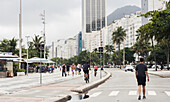 Junger Mann geht auf der Straße neben der Strandpromenade am Copacabana Beach, Rio de Janeiro, Brasilien, Südamerika