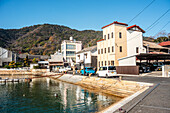 Gebäude an der Uferpromenade von Tomonoura, mit einem türkisfarbenen Wasserbecken davor, Tomonoura, Honshu, Japan, Asien