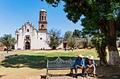 Mexiko, Bundesstaat Michoacan, Tzintzuntzan, zwei Mexikaner auf einer Bank vor der Kirche