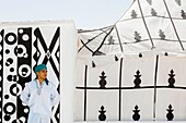 Marocco, Oued Ed-Dahab, Dakhla, Les Dunes Eco-lodge, young Moroccan in traditional clothes in front of a tent decorated with African tribal patterns