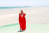 Marocco, Oued Ed-Dahab, Dakhla, PK25 Resort, young Moroccan woman in traditional clothes on a beach at low tide