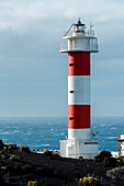 Spanien, Kanarische Inseln, La Palma, Blick auf einen Leuchtturm und die ihn umgebende Saline am Meer, auf einer Vulkaninsel