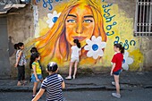 Georgia, Tbilisi, Old Tbilisi or Dzveli Kalaki, children playing in front of a mural