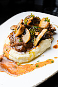 Succulent pork cheeks cooked in Pedro Ximene reduction, served over creamy mashed potatoes, garnished with mushrooms and chives.