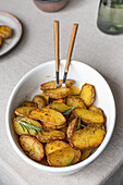 From above bowl of golden roasted potatoes seasoned with herbs, captured from an angled view, ready to be enjoyed.