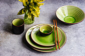 Elegant green ceramic dinner set with chopsticks, showcasing a bright table setting.