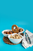 Healthy assorted nuts including walnuts, pistachios, and hazelnuts presented in a segmented bowl on a blue background, enhanced by wooden and wicker textures.