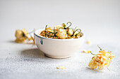 A ceramic bowl filled with delicate dried roses rests against a soft, textured white background, offering a simplistic yet elegant decorative theme