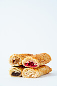 A selection of delicious layered puff pastry rolls with various sweet and savory fillings, arranged on a simple white background for a clean presentation.