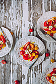 Elegante Teller mit buntem Tomatensalat mit Kirschtomaten stehen auf einem rustikalen, weiß gestrichenen Holztisch bereit, begleitet von Weingläsern