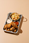 Delicious fried chicken wings accompanied by golden potato wedges served with creamy and tangy sauces.