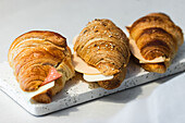 Delicious fresh croissants with slices of cheese and ham served on tray on table