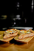 Close-up image capturing authentic Georgian Khachapuri, featuring a crispy crust, melted cheese, and a perfectly cooked egg, served on rustic wooden boards in a dimly lit setting