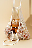 Various freshly baked sourdough breads nestled in an eco-friendly mesh bag, highlighted by a warm beige background.