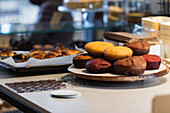 Assorted sweet vegan sponge cakes placed on wooden tray on counter in bakery