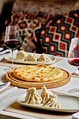 A tempting selection of Georgian cuisine featuring Khachapuri, Khinkali, and wine served on a wooden board and traditional plates