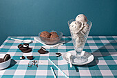 A refreshing ice cream sundae accompanied by chocolate biscuits laid out on a blue and white checkered tabletop