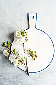 A pristine white ceramic cutting board adorned with delicate cherry blossoms offers a fresh, springtime vibe