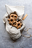 Selbstgebackene Lebkuchen in Form von Sternen, eingebettet in einen grauen Leinenbeutel mit einem rustikalen Etikett auf einer strukturierten Oberfläche.