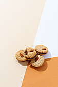 Gourmet nut biscuits arranged artistically on a dual-tone beige and brown background, evoking a sense of handmade quality.