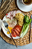 A nutritious meal with sliced reddish, tomato, celery, a fried egg, and bulgur cereal accompanied by a cup of green tea, arranged on a woven placemat.