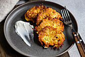 Crispy golden potato american pancakes placed on a slate plate with a dollop of sour cream beside them, ready to enjoy.