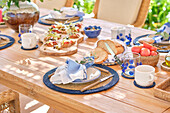 A close-up of a luxurious breakfast served on a sunny terrace, showcasing a variety of bread, fruits, and vibrant table settings