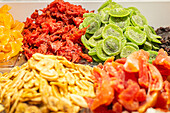 A vibrant selection of dried fruits, including kiwi, hibiscus flower, papaya, and banana slices, showcased in a market setting