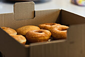 Leckere vegane Krapfen und Berliner in einer Pappschachtel zum Mitnehmen auf einem Tisch in einer Backstube