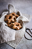 From above view of homemade gingerbread star-shaped cookies wrapped in a gray cloth, creating a cozy and rustic vibe. A pair of scissors adds a touch of craft to the scene, emphasizing the handmade quality.