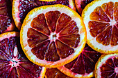 From above of vibrant close-up of juicy Sicilian blood orange slices, with a focus on their rich, red hues and fresh citrus details.