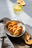 Palmiers oder Elefantenohren, Blätterteigkekse in einer Schale auf einem Betontisch an einem sonnigen Tag