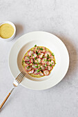 Overhead image featuring roasted radishes arranged on a plate with a creamy green tahini sauce, served alongside a small bowl of extra sauce.