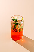 A vibrant glass of berry-orange lemonade garnished with fresh mint and a lemon slice, perfect for a warm summer day.