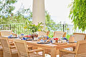 An inviting breakfast spread arranged on a wooden table on a terrace overlooking the sea, complete with fresh pastries, fruits, and coffee