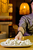 A chef in a Georgian restaurant, dressed in a crisp uniform, delicately arranges handmade khinkali on a sleek white plate, under warm ambient lighting