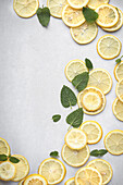 Top view of sliced fresh lemons and assorted herbs arranged on a light background with copy space.