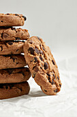 Close-up of a tempting stack of chocolate chip cookies with a bitten cookie in the foreground, arranged on crinkled parchment paper