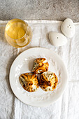 A rustic presentation of Georgian khinkali, traditional dumplings, served on a white plate alongside a glass of white wine and salt shaker, symbolizing Georgian cuisine