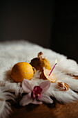 A serene still life featuring fresh lemons, a slice with a birthday candle, alongside a flower and nut, on a fluffy white surface