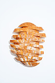 An image showing a freshly baked sourdough bread cut into neat slices, arranged artistically against a white background.