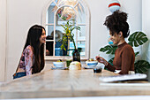 Side view of diverse female friends sitting at table and eating tasty poke while spending weekend in restaurant