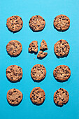 Flat lay photography of twelve chocolate chip cookies arranged on a vibrant blue background