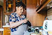 A senior woman is engaged in the homely activity of cooking, skillfully preparing an eggplant in her kitchen