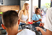 Siblings happily engage in baking cookies together in a sunlit, modern kitchen, showcasing a joyful family activity