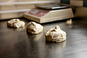 Freshly prepared pizza dough portions sit on a shiny stainless steel kitchen counter, ready for baking